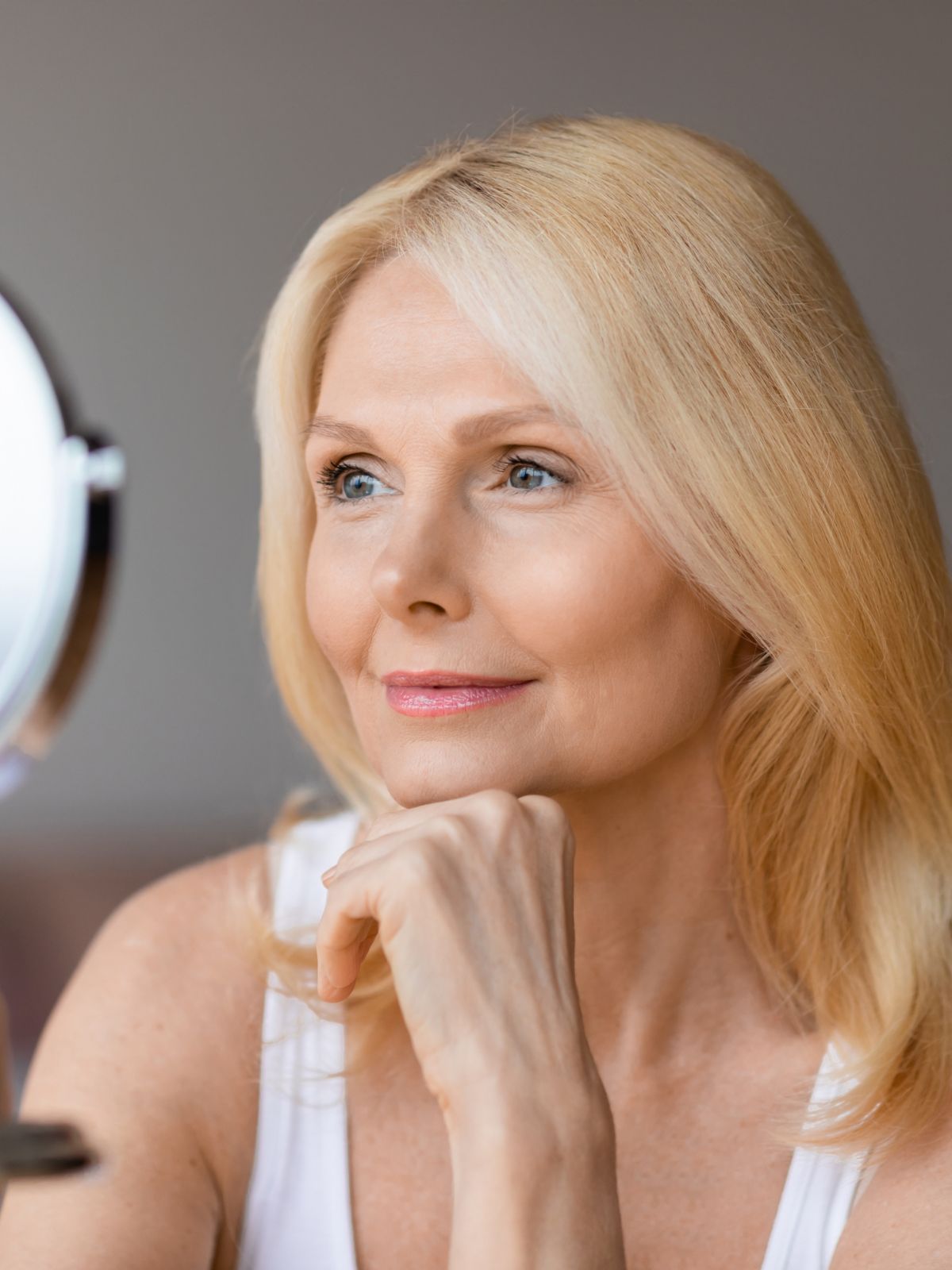 mature woman looking at her face in a mirror